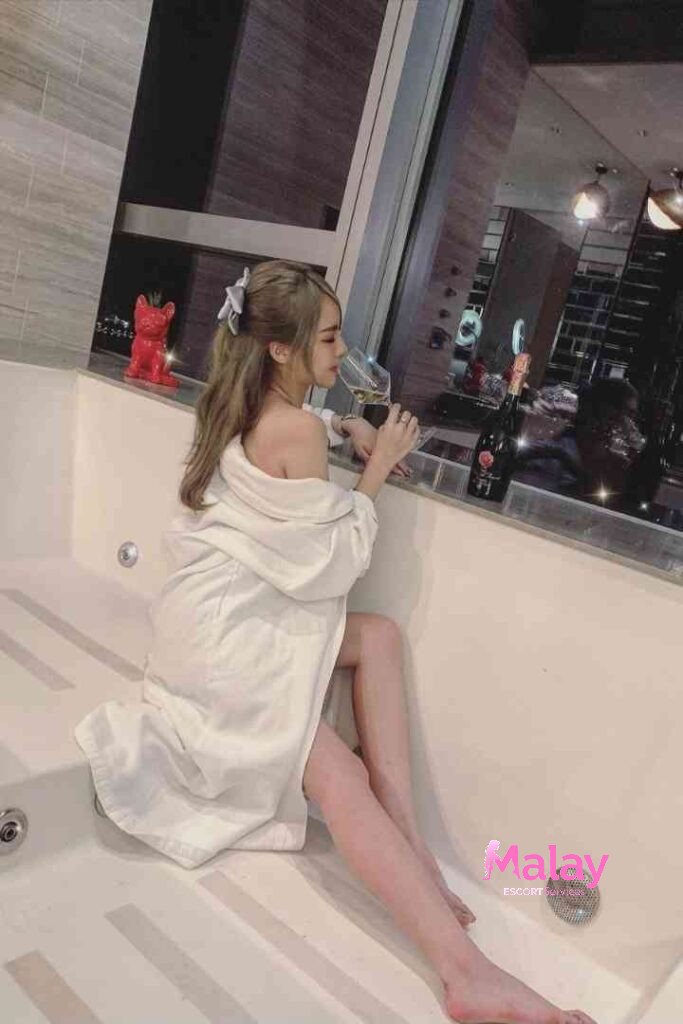 Malay Escort Service Woman in bathrobe with wine glass in a bathtub at night KL Escort Girl