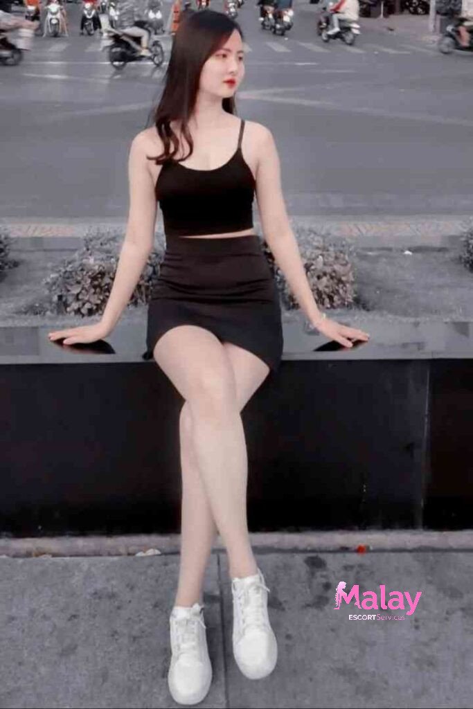 Malay Escort Service Young woman in black crop top and skirt sitting on a ledge outdoors KL Escort Girl Malay Escort KL Real KL Escorts Ready for You Malay Escort Service Young woman in black crop top and skirt sitting on a ledge outdoors KL Escort Girl