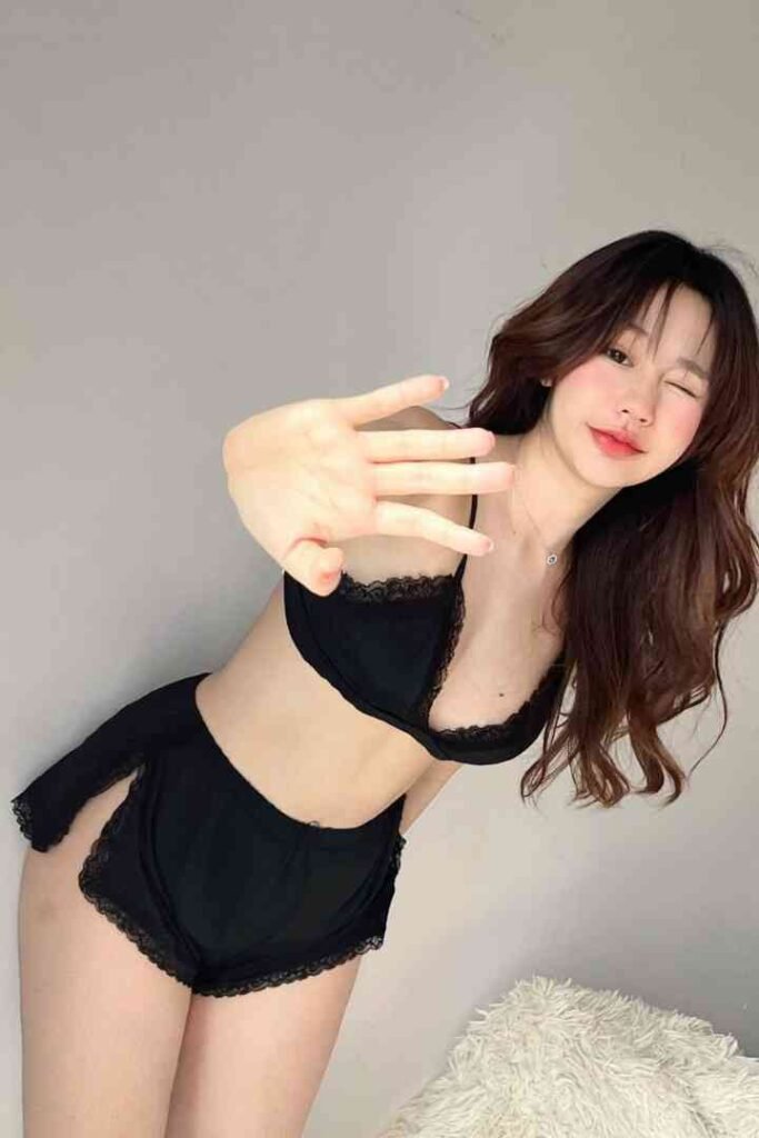 Malay Escort Service Young woman in black lingerie posing with hand outstretched KL Escort Girl