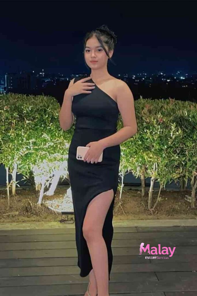 Malay Escort Service Young woman in a black one shoulder dress with a high slit KL Escort Girl