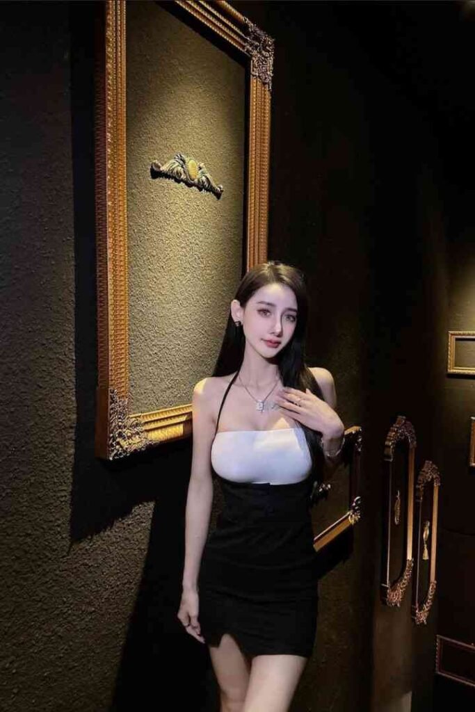 Malay Escort Service A woman in a black and white dress poses in a room with gold framed pictures KL Escort Girl