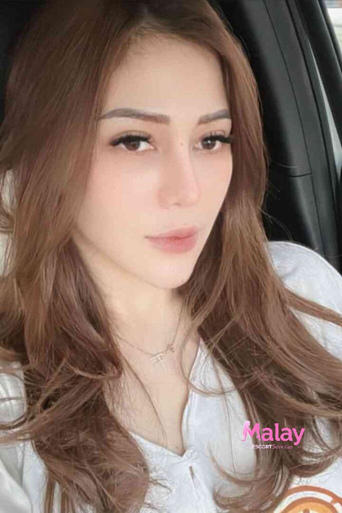 Malay Escort Service Woman with long brown hair and light makeup wearing a white top and a delicate necklace KL Escort Girl