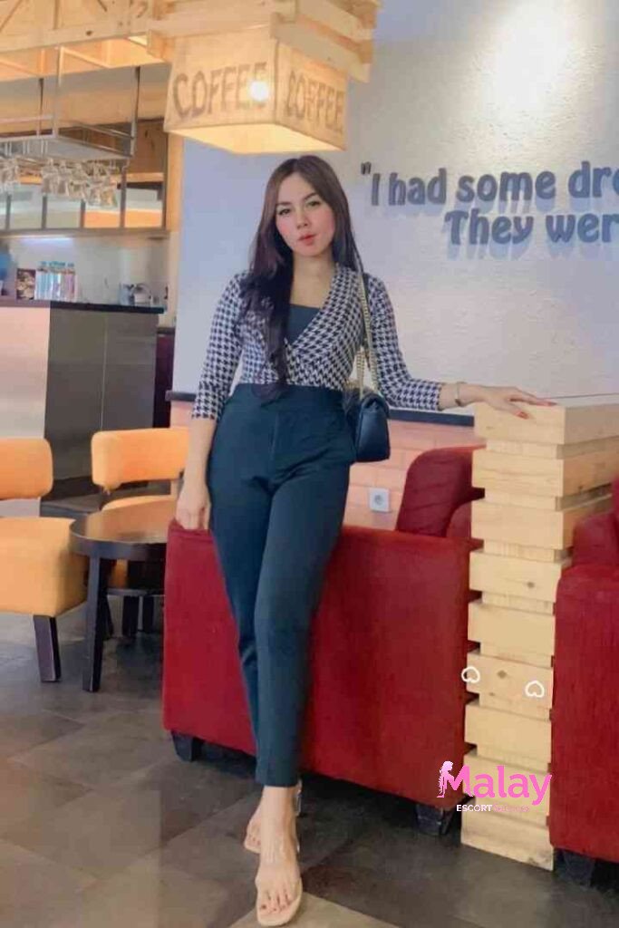 Malay Escort Service Woman in black and white patterned top and black pants posing in a cafe KL Escort Girl