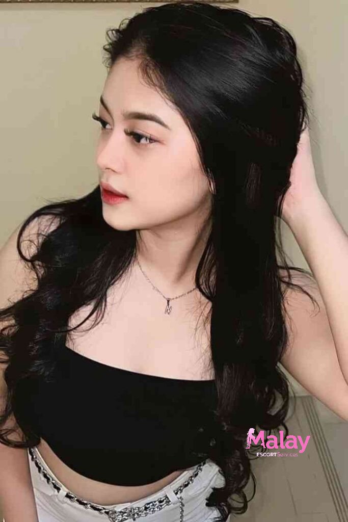 Malay Escort Service Young woman with long dark wavy hair and a black tube top KL Escort Girl