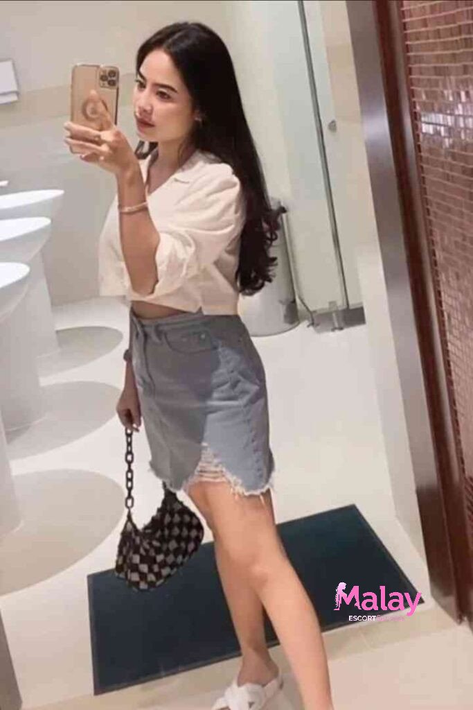 Malay Escort Service Woman in a white crop top and denim skirt taking a mirror selfie in a bathroom KL Escort Girl Malay Escort KL Real KL Escorts Ready for You Malay Escort Service Woman in a white crop top and denim skirt taking a mirror selfie in a bathroom KL Escort Girl