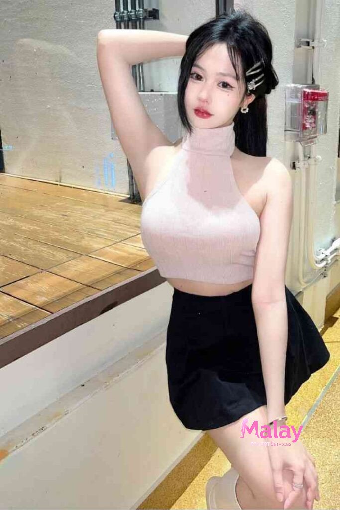 Malay Escort Service Young woman in a pink halter top and black skirt poses with arm raised KL Escort Girl Malay Escort KL Real KL Escorts Ready for You Malay Escort Service Young woman in a pink halter top and black skirt poses with arm raised KL Escort Girl