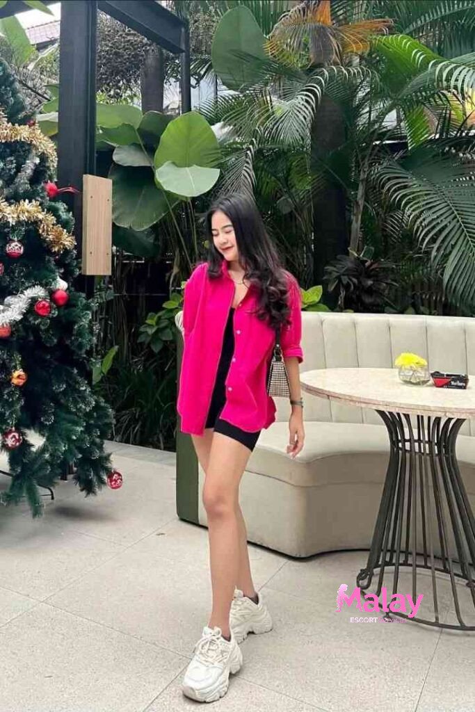 Malay Escort Service Young woman in a pink shirt and black shorts stands by a Christmas tree KL Escort Girl Malay Escort KL Real KL Escorts Ready for You Malay Escort Service Young woman in a pink shirt and black shorts stands by a Christmas tree KL Escort Girl