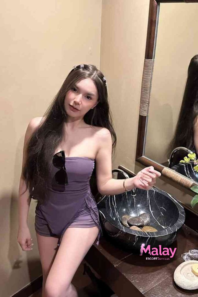 Malay Escort Service Woman in a purple strapless swimsuit with ruching stands by a marble sink KL Escort Girl Malay Escort KL Real KL Escorts Ready for You Malay Escort Service Woman in a purple strapless swimsuit with ruching stands by a marble sink KL Escort Girl