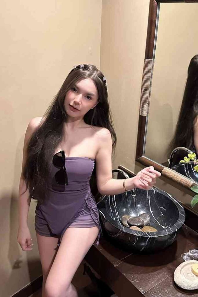 Malay Escort Service Woman in a purple strapless swimsuit posing by a marble sink in a spa KL Escort Girl