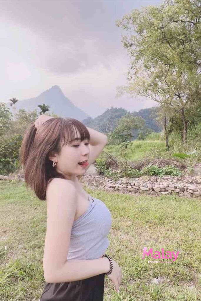 Malay Escort Service Young woman with brown hair sticking her tongue out in a grassy field with mountains KL Escort Girl Malay Escort KL Real KL Escorts Ready for You Malay Escort Service Young woman with brown hair sticking her tongue out in a grassy field with mountains KL Escort Girl