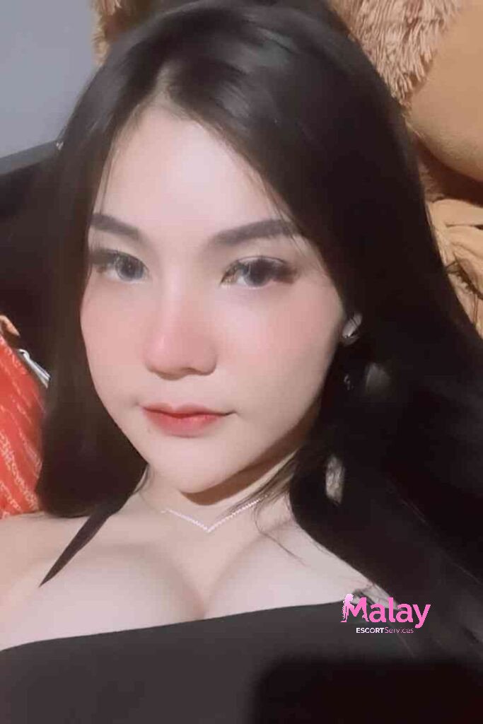 Malay Escort Service Young woman with dark hair and light colored eyes wearing a black top and necklace KL Escort Girl