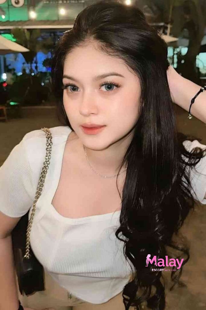 Malay Escort Service Young woman with long dark hair and blue eyes wearing a white top KL Escort Girl