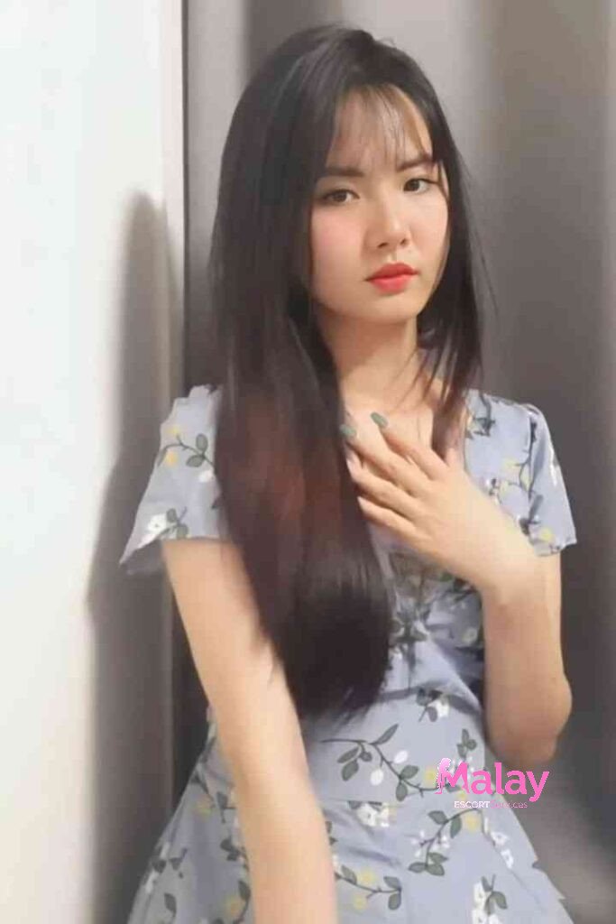 Malay Escort Service Young woman with long dark hair and bangs wearing a floral dress poses with her hand on her chest KL Escort Girl Malay Escort KL Real KL Escorts Ready for You Malay Escort Service Young woman with long dark hair and bangs wearing a floral dress poses with her hand on her chest KL Escort Girl